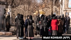 Studente universitare afgane oprite de personalul de securitate taliban stau lângă o universitate din Kabul, la 21 decembrie 2022