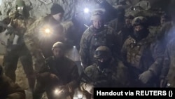 Bărbați în uniforme militare care pretind că sunt luptători ai grupului de mercenari Vagner și șeful acestuia Evgheni Prigojin, într-o poză despre care se crede că s fost făcută într-o mină de sare de la Soledar, regiunea Donețk, 10 ianuarie 2023.
