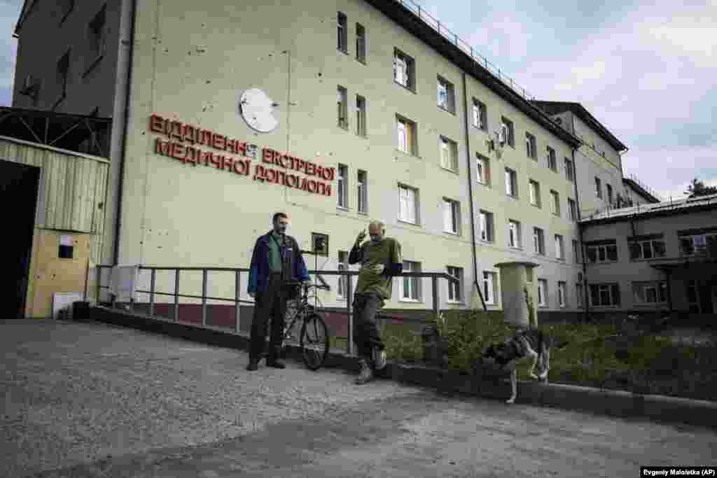 Пациентот Вадим Назаров (лево) разговара со волонтерот Денис Жмакин пред болницата. Болницата беше единствената медицинска установа која остана отворена кога руските трупи го презедоа Изум во почетокот на март. Градот се врати во рацете на Украина во&nbsp; минатиот месец за време на контраофанзивата која им нанесе удар на воените цели на Москва.
