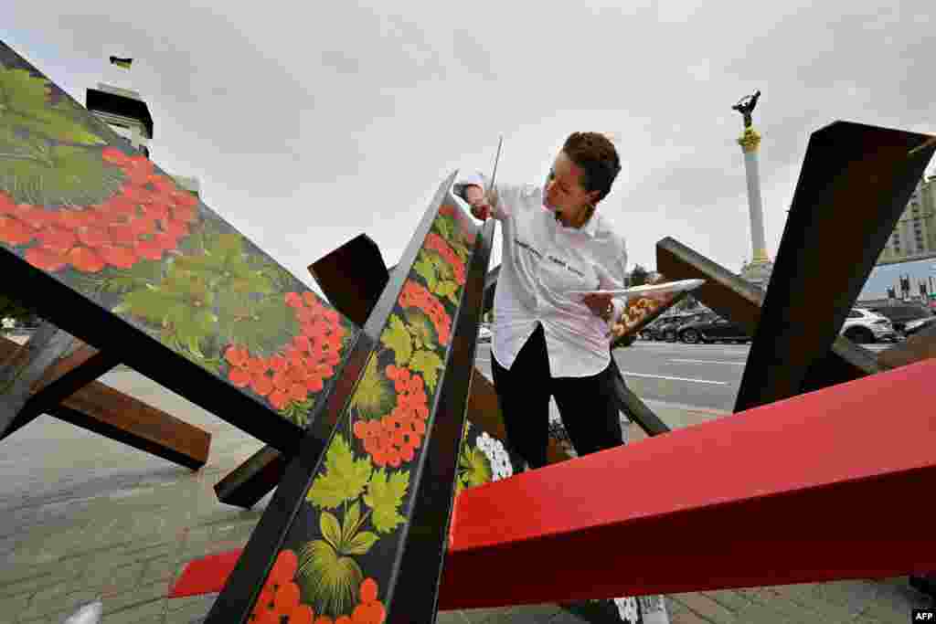 Українська художниця Варвара Логвин розмальовує протитанкові загородження, відомі як «чеські їжаки», традиційним українським петриківським розписом. Київ,15 серпня 2022 року