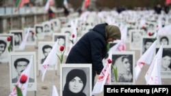 „მუჯაჰედინ-ე-ხალღის“ წევრი 1988 წელს დახოცილთა პორტრეტების ფონზე. 2019 წლის 29 ოქტომბერი, პარიზი