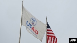 Egy USAID-lobogó és egy amerikai zászló az Egyesült Államok Nemzetközi Fejlesztési Ügynöksége (USAID) washingtoni központja előtt 2025. február 3-án