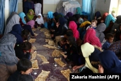 Internally displaced Afghans eat breakfast after arriving from Jaghori district of Ghazni fleeing ongoing battles between Taliban and Afghan security forces, in Ghazni Province on November 12