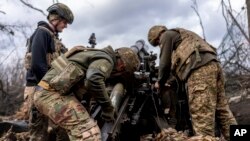 Militarii ucraineni încarcă obuze într-un obuzier înainte de a trage spre pozițiile rusești în regiunea Harkov (ilustrație generică).