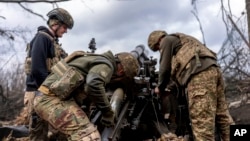 Ukrainian soldiers load a shell into howitzer before firing toward Russian positions in the Kharkiv region on March 12. 