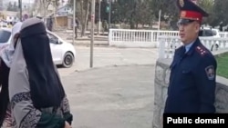 Un polițist stă de vorbă cu o femeie cu niqab la Oș, în aprilie 2025.