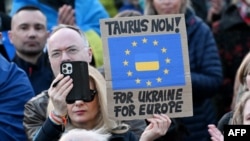 Жена държи плакат с надпис "Таурус сега - за Украйна, за Европа" по време на демонстрация в подкрепа на Украйна пред Бранденбургската врата в Берлин, 9 март 2025 г. 