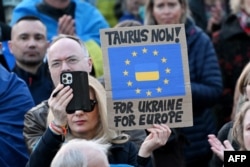 ბერლინში, ბრანდენბურგის კარიბჭესთან გამართული დემონსტრაციის მონაწილეს უჭირავს უკრაინის მხარდამჭერი პლაკატი წარწერით: „Taurus now - for Ukraine, for Europe“, („Taurus-ი ახლავე - უკრაინისთვის, ევროპისთვის“), 2025 წლის 9 მარტი.