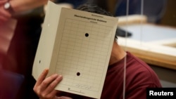 Подсъдимият Еяд ал Гариб крие лицето си с папка по време на процеса срещу него в Германия