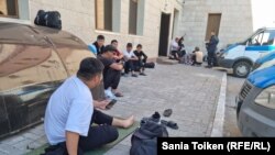 Задержанные перед зданием министерства труда и доставленные в полицейский участок безработные жители Жанаозена сидят на земле после назначения им штрафов в полиции. Нур-Султан, 23 июня 2022 года