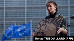 NJë grua duke protestuar para selisë së Këshillit të Evropës në Bruksel. Ajo mban në duar një pano ku shkruan: "Shpëtoni mbrojtësit e Azovstalit. Belgjikë, 16 maj 2022.