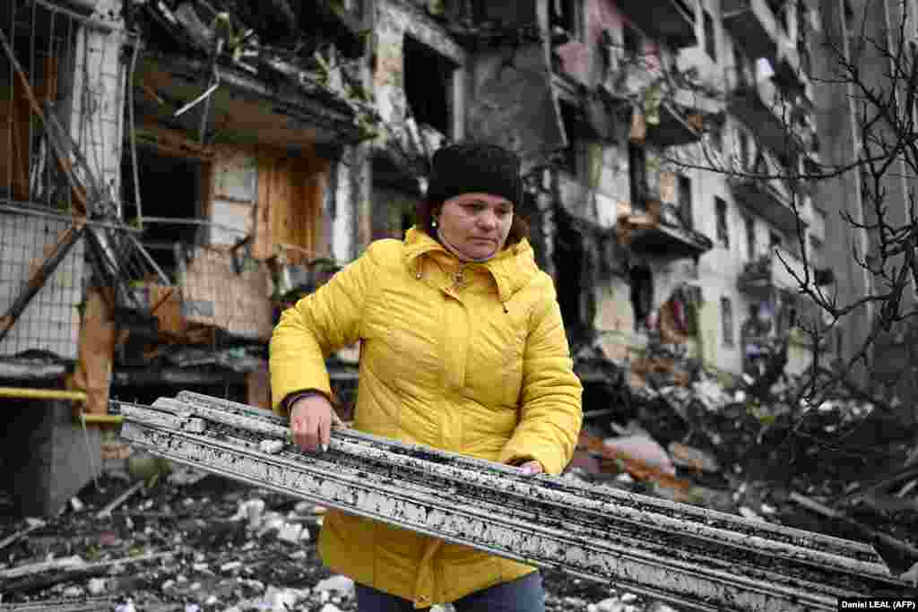 Украинка расчистува во урнатините од станбена зграда во едно од предградијата на Киев, 25 февруари 2022