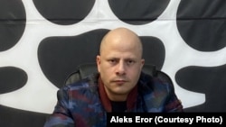 Водачот на Левијатан, Павле Бихали, во неговата канцеларија во центарот на Белград со логото на групата зад себе. Фото: Алекс Ерор