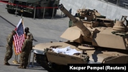 Американски войници стоят с полски и американски знамена до танк M1/A2 "Ейбрамс" на 30-тото Международно изложение на отбранителната промишленост в Киелце, Полша, 5 септември 2022 г.