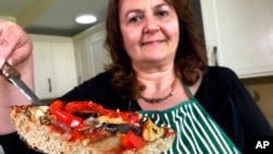 Tiziana di Costanzo, cofondatoare a Horizon Insects, ține în mână o felie de pizza făcută cu praf de greieri, în bucătăria sa din Londra (foto de arhivă).