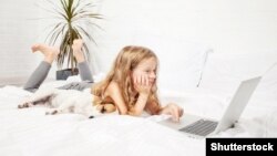 Маленькая девочка с ноутбуком и собакой, иллюстративное фото