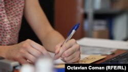 Funcționar al CNSAS completează cu pixul formulare pentru cei care solicită documente.