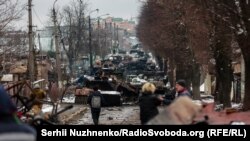 Civili posmatraju kolonu uništenih ruskih oklopnih vozila u Buči, u blizini Kijeva, 1. marta 2022.