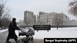 Egy nő babakocsit tol az Egyesült Államok kijevi nagykövetsége előtt. Ukrajna szerint korai volt a döntés az amerikai diplomaták családtagjainak hazahívásáról. 2022. január 24. 