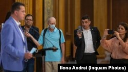 AUR și USR sunt cele mai importante partide din opoziție. Ele sunt, la rândul lor, diametral opuse în privința politicilor publice pe care le promovează. În imagine George Simion, liderul AUR, (cu costum negru), în timp ce transmite pe Facebook o conferință de presă a USR.