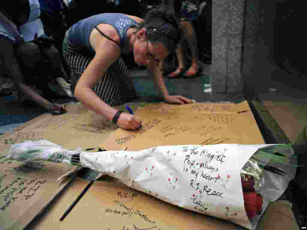 Обожавател на Мајкл Џексон се потпишува во знак на сеќавање на Кралот на поп музиката - epa01774422 A fan of the late US pop star Michael Jackson signs a cardboard memorial in front of the Apollo Theater in Harlem, New York USA, 25 June 2009. Pop star Michael Jackson died 25 June after collapsing after a cardiac arrest at his home in Los Angeles, officials said. He was 50. The former King of Pop, whose life of stardom and scandal kept him permanently in the headlines, was found unconscious at his rented Bel Air mansion and was rushed to the UCLA Medical Centre. EPA/PETER FOLEY