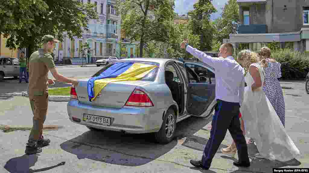 A Nemzeti Gárda katonája, Ihor és menyasszonya, Kira kifelé jövet a pincéből, ahol az esküvőjüket tartották Harkivban június 23-án. A városban a házasságkötéseket gyakran a föld alatt tartják az orosz támadások miatt