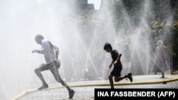 Një person së bashku me djalin e tij freskohen në Koln të Gjermanisë. 18 korrik 2022. 