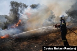 Vatrogasac radi na gašenju šumskog požara koji gori u Palliniju, blizu Atene, Grčka, 20. jula 2022.