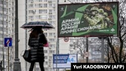 Пешак поминува покрај билборд со руски војници, на улица во Москва, Русија, 24.10.2022