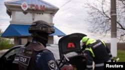 Forțe de ordine controlează un autoturism la un punct de control în periferia orașului Tiraspol, 27 aprilie 2022. 