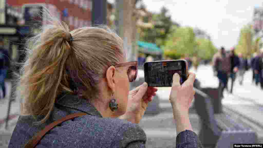 Një qytetare fotografon protestuesit të cilët marshuan nga sheshi Zahir Pajaziti deri te Teatri Kombëtar, që gjendet përballë ndërtesës së Qeverisë së Kosovës.&nbsp;