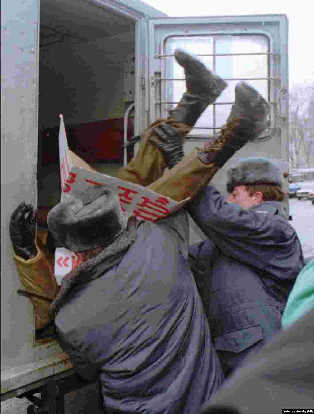 Милиция задерживает участника акции протеста в Киеве 12 января 1996 года. Несколько членов украинского парламента организовали протест против договора о безъядерном статусе Украины. В то время как силы охраны порядка загружают его в милицейский фургон, он держит плакат с требованием отставки министра обороны Украины Валерия Шмарова