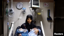 A palesztin Iman Abu Mutlaq tartja újszülött ikreit, Uday és Hamza Abu Odah-t karjában a Nasszer kórház szülészeti osztályán, a Gázai övezet déli részén fekvő Hán Juniszban 2023. november 2-án