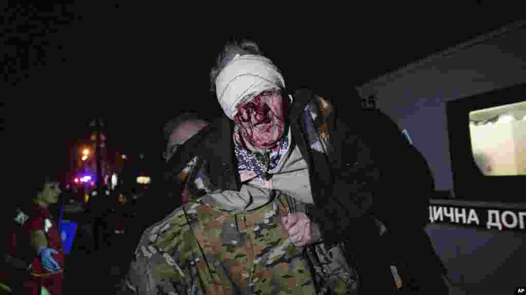 Украински војник изнесува повредена жена од нејзиниот дом откако бил погоден во руските воздушни напади врз Киев