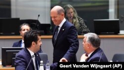 Olaf Scholz német kancellár (k) kezet fog Kiril Petkov bolgár miniszterelnökkel, mellettük Orbán Viktor miniszterelnök egy EU-csúcson Brüsszelben 2022. június 23-án