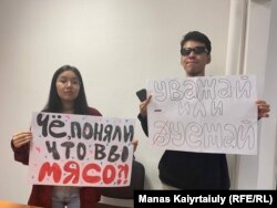Qaragoz Qasym (majtas) dhe Aisultan Qudaibergen u arrestuan në aeroportin Almati teksa mbanin postera me mbishkrime: "A e kuptuat se jeni mish për top?" dhe "Ose respekt ose largohu".