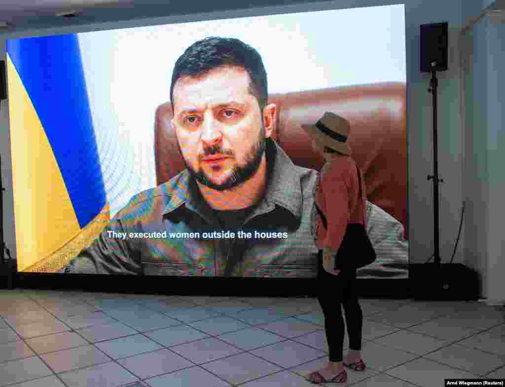 Egy nő az Orosz háborús bűnök házában berendezett kiállításon nézi Volodimir Zelenszkij ukrán elnök egyik korábbi beszédét a davosi Világgazdasági Fórumon május 22-én