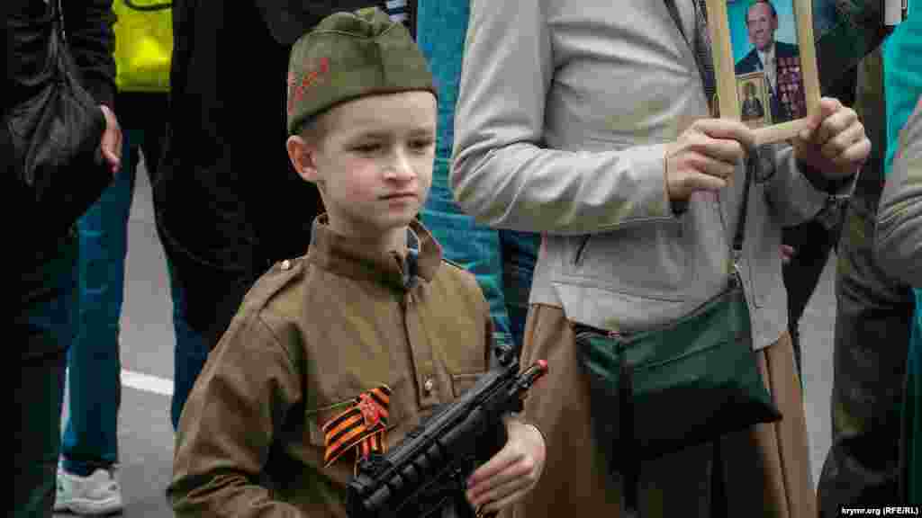A young participant carries a toy gun in Sevastopol, Crimea, during the Immortal Regiment march on Victory Day, observed on May 9.