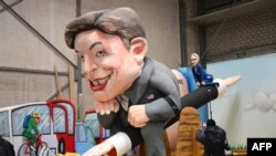 Car alegoric pregătit pentru carnavalul de la Köln (Germania): în față Elon Musk, în spate „prietena” sa din Germania, șefa partidului de extremă-dreapta AfD, Alice Weidel.