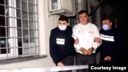 A smiling Mikheil Saakashvili is shown in handcuffs in a video released by the Georgian Interior Ministry.