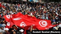 Demonstranti nose transparente i zastave tokom protesta protiv predsjednika Kaisa Saida, u Tunisu 15. maja 2022. 