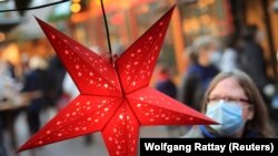 Një grua me që bartë maskë fytyre derisa lëvizë rrugëve të një qyteti në Gjermani. 