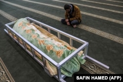 Egy férfi ül egy mecsetben Gailan Diler iraki kurd migráns hazaküldött holtteste mellett. A férfi akkor halt meg, amikor illegálisan próbált Belaruszon keresztül Lengyelországba jutni. Temetését Arbilban, Irak autonóm kurd régiójának fővárosában tartották 2021. november 15-én