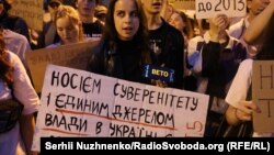 კიევში საპროტესტო აქციის მონაწილეს უჭირავს პლაკატი წარწერით: უკრაინის ხელისუფლება უკრაინის ხალხია