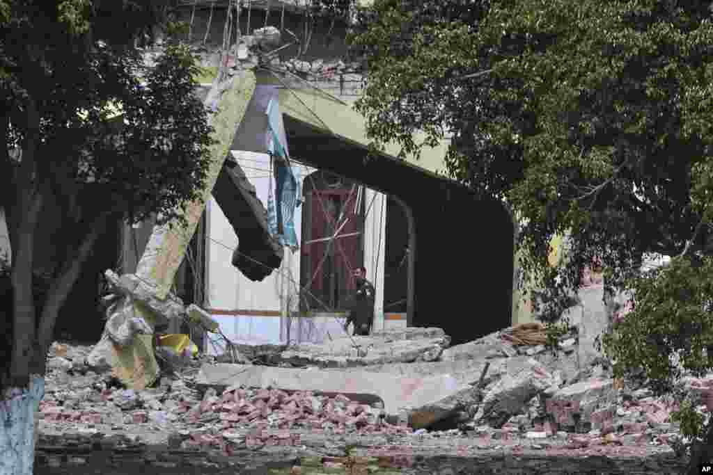 Приватно обезбедување покрај урнатините на зграда по индискиот ракетен напад во Муридке, град во пакистанската провинција Пенџаб, среда, 7 мај 2025 година.