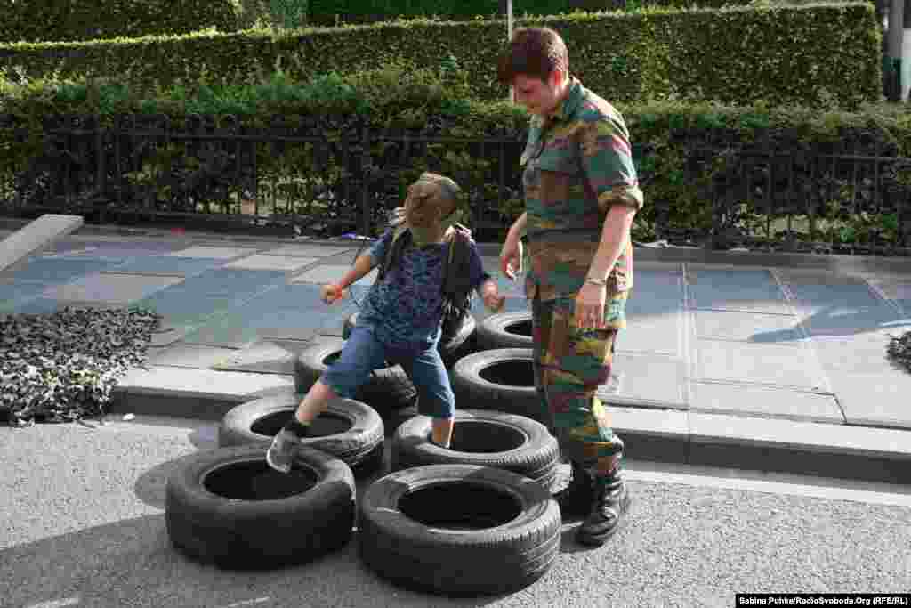 Бельгійські військові організували різні ігри та атракціони для дітей. Жінка-офіцер допомагає хлопчику подолати смугу перешкод