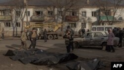 Un ofițer de poliție ucrainean inspectează cadavrele persoanelor ucise și puse în saci de plastic la locul unui atac rusesc cu rachete la Izium, Harkov - 4 februarie 2025.