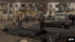 Un ofițer de poliție ucrainean inspectează cadavrele persoanelor ucise și puse în pungi de plastic la locul unui atac rusesc cu rachete la Izium, Harkov - 4 februarie 2025.