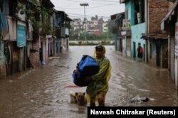 Мужчина с сумкой в руках пробирается по затопленной улице в Катманду, Непал, 4 октября 2025 года