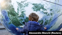 Dijete grli balon u obliku planete Zemlje tokom okupljanja u povodu početka Konferencije za klimatske promjene (COP21), Rim, Italija, 2015.